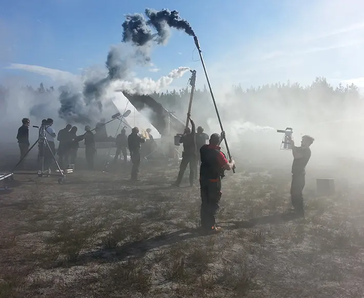 Film crew setting up special effects with smoke outdoors